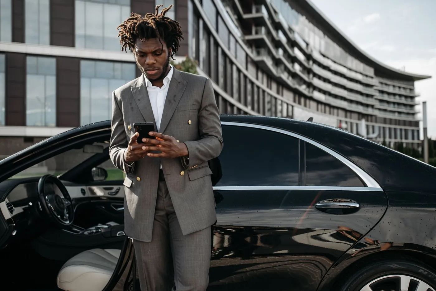 Utilisateur consultant son smartphone à côté d'une voiture partagée en ville